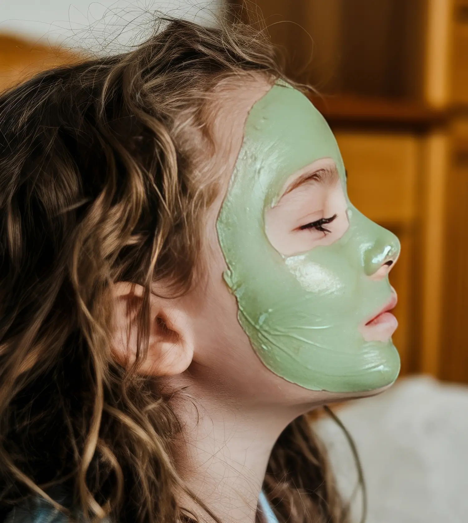 A young girl wearing a green face mask during her Kiddies Facial experience at Pause Spa