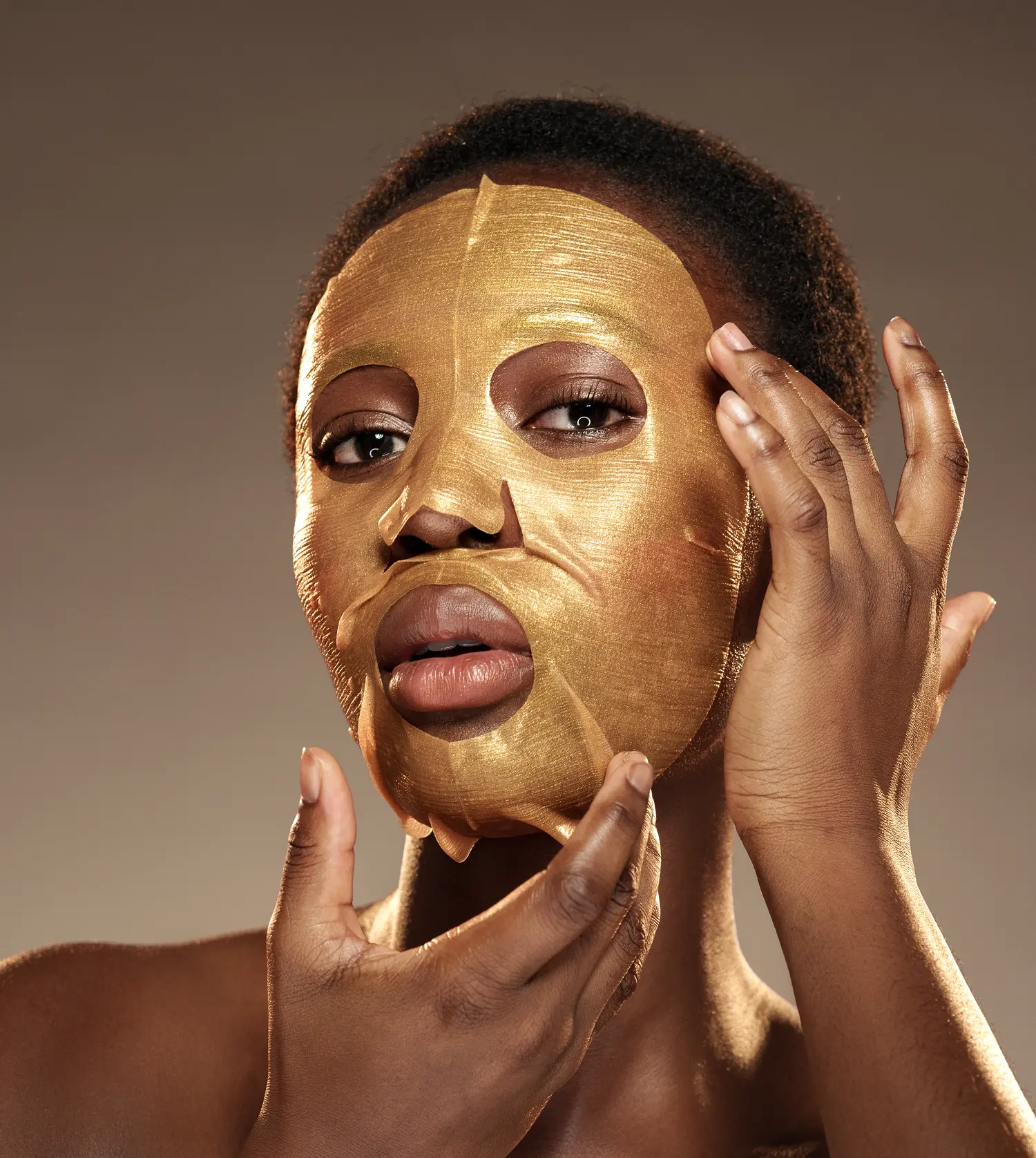 African woman wearing a gold face mask during her Signature Gold Facial experience at Pause Spa