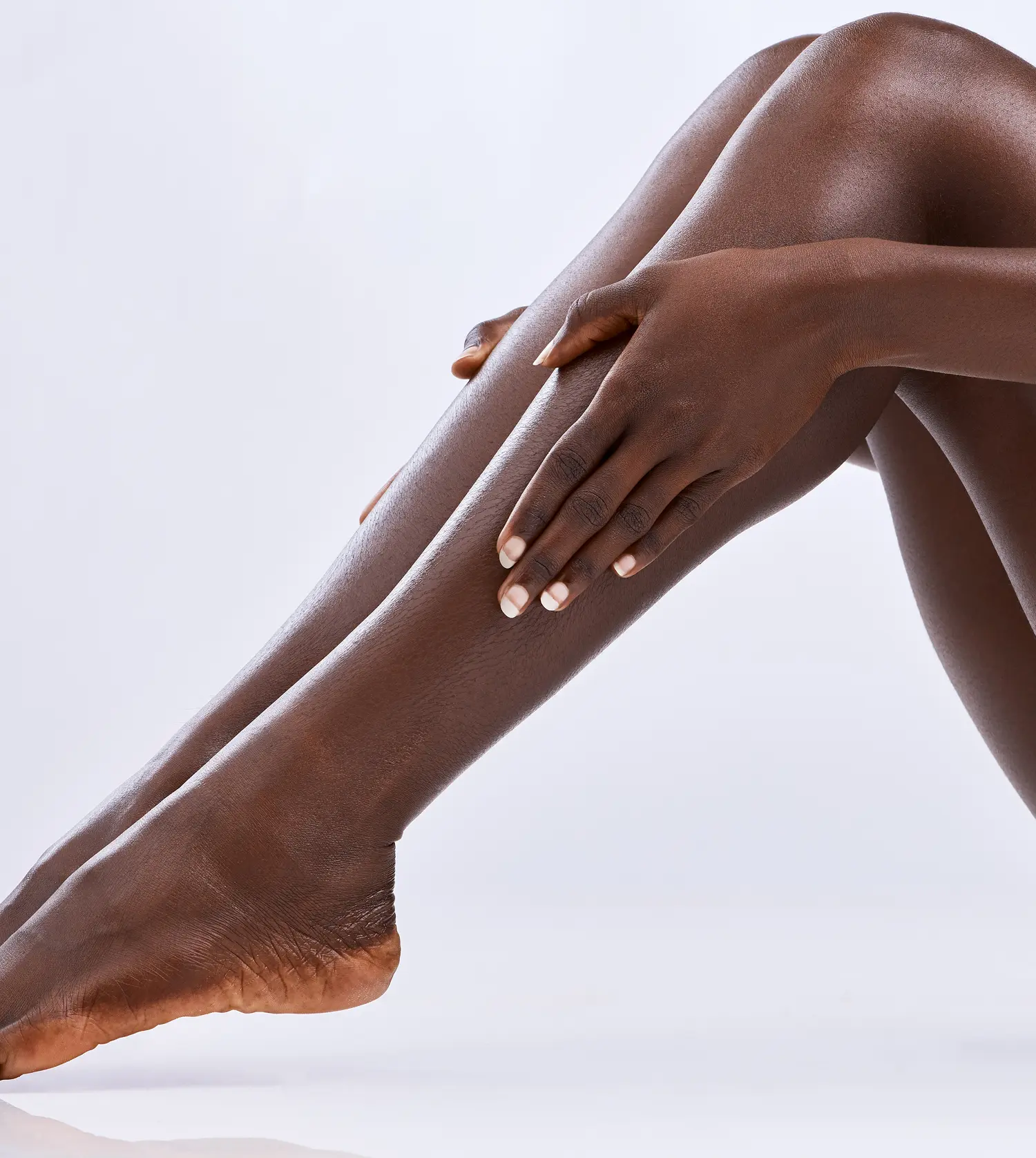 African woman showing off her legs against a white background after her Half Leg Wax experience at Pause Spa
